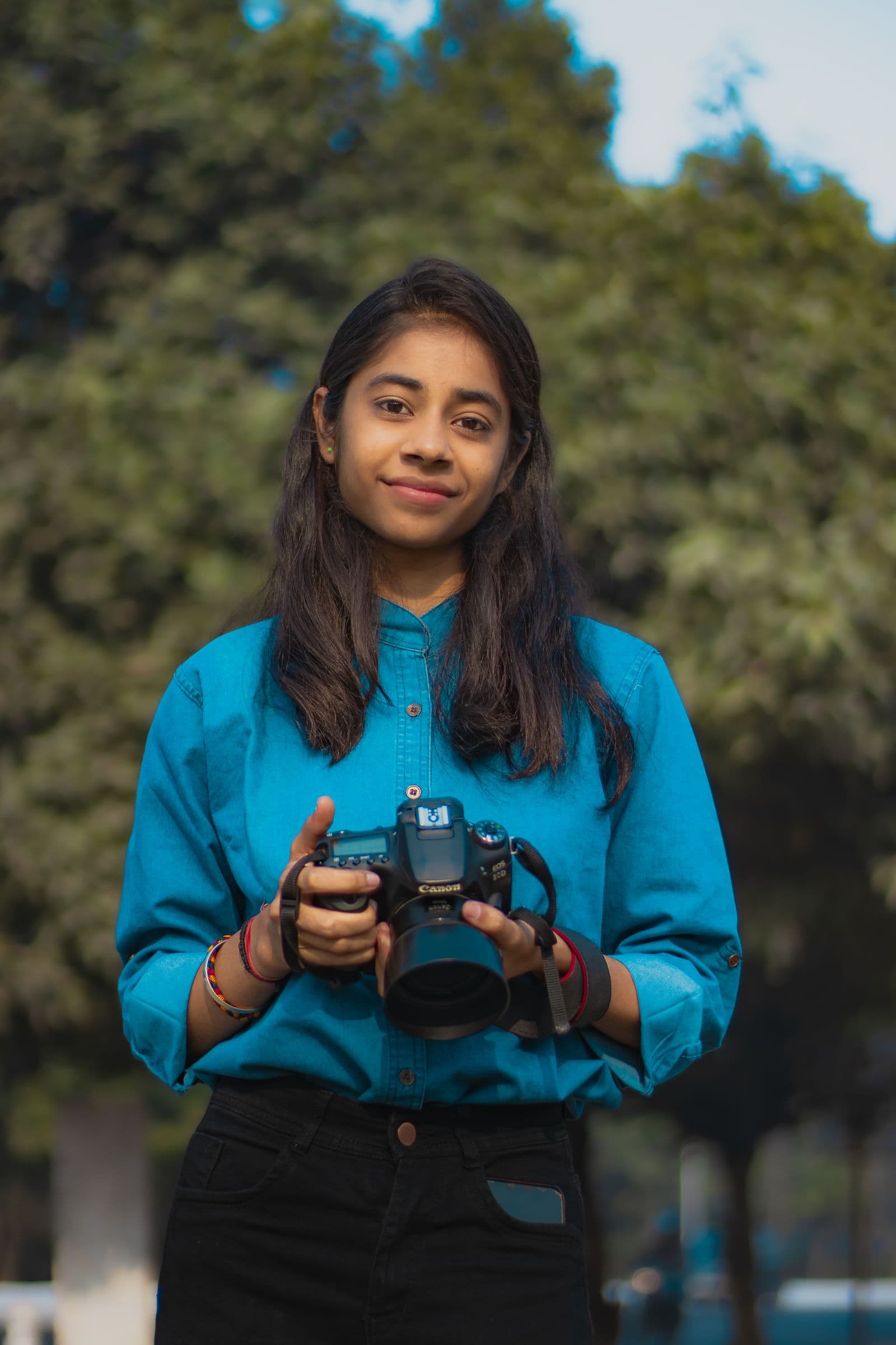 A young photographer holding her camera outdoors